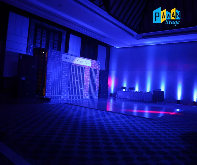  A large room with blue lighting features a dance floor, set in a jail-themed Udaipur resort ballroom for a family event night.

