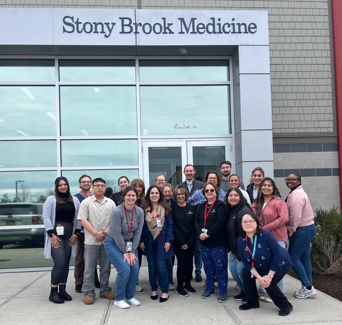 Group of Stony Brook Medicine staff members standing together in front of their building entrance.