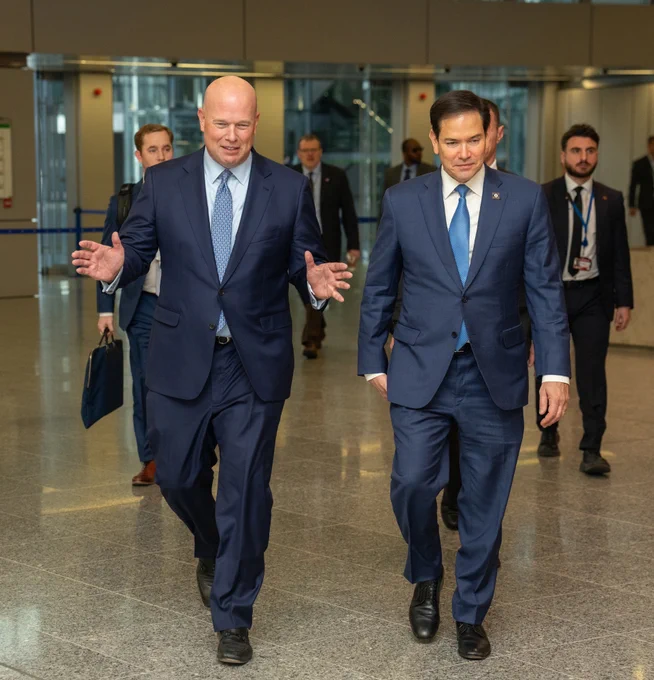 Secretary Rubio and U.S. Ambassador to NATO Matt Whitaker  are walking and engaged in conversation. Other individuals are in the background, some of whom are also in business attire. (Official State Department photo by Freddie Everett)
