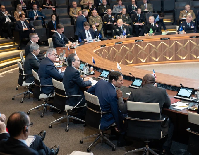 Secretary Rubio sits behind a microphone and next to his counterparts in a conference conference room with a round table. Flags from different countries are visible and there are additional people seated in the background. (Official State Department photo by Freddie Everett)