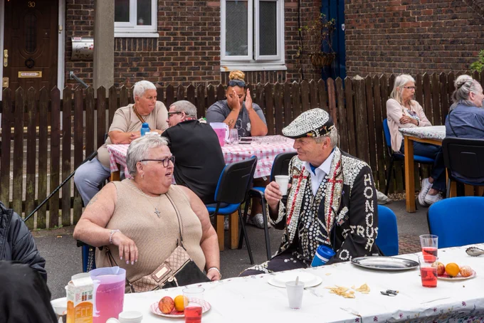 a pearly king joins people enjoying a street party