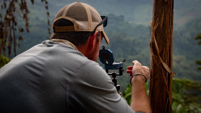 A man takes a sighting with a compass in a hilly jungle area. (Photo Credit: Staff Sgt. Cole Yardley, Defense POW/MIA Accounting Agency; modified by the Army Geospatial Center) 