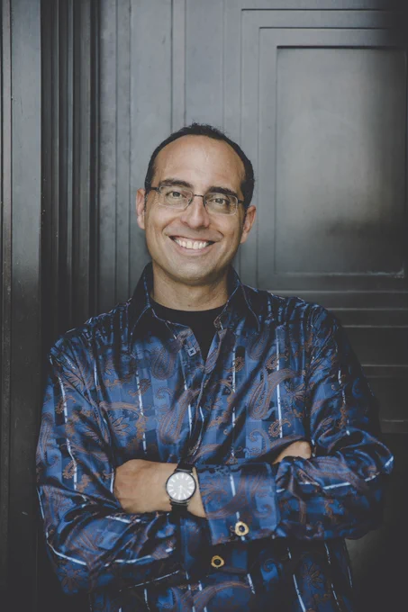 Philip Metres smiles and stands with his arms crossed.