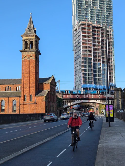two cyclists riding down deansgate 