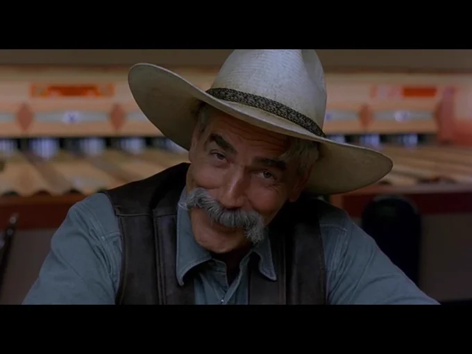 The Stranger smiles goofily at the viewer as he continues to deliver the movie's closing monologue.