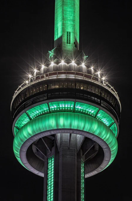 Closeup of the CN Tower at night lit green / Gros plan de la Tour CN illuminée en vert la nuit.