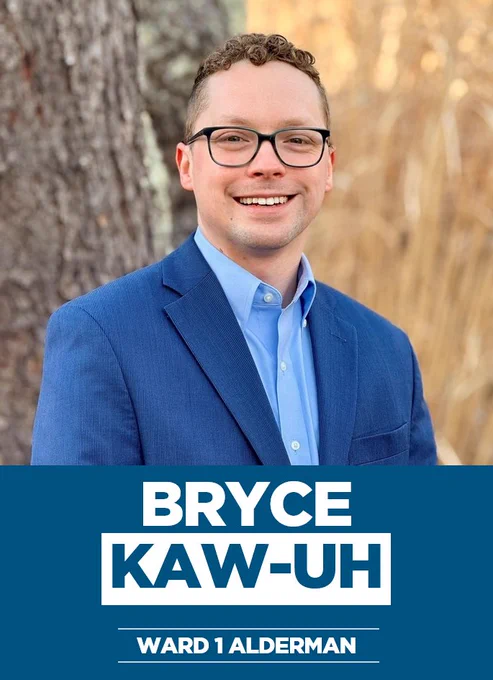 A photo of Bryce Kaw-uh outdoors in a blue suit with text below that says Bryce Kaw-uh for Ward 1 Alderman.