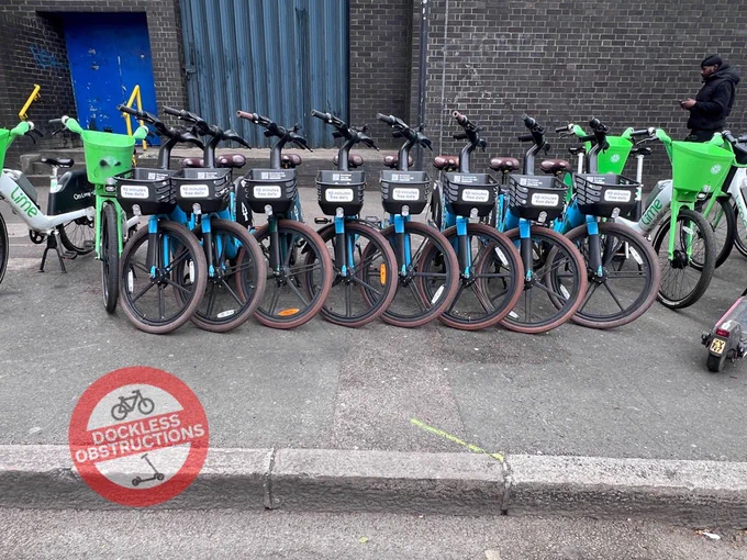 Rows of Forest bikes deployed on pavement for hire surrounded by lime bikes.