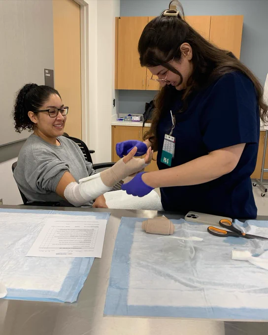 Two physician assistant program students practice arm splinting. 
