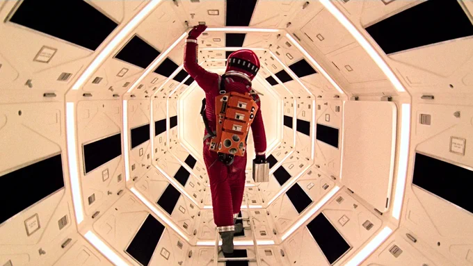 A person wearing a red spacesuit, standing inside a futuristic spacecraft