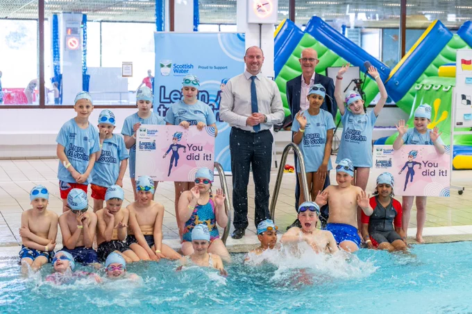 Health Secretary Neil Gray with children  in light blue T-shirts and caps learning to swim at the Royal Commonwealth Pool.