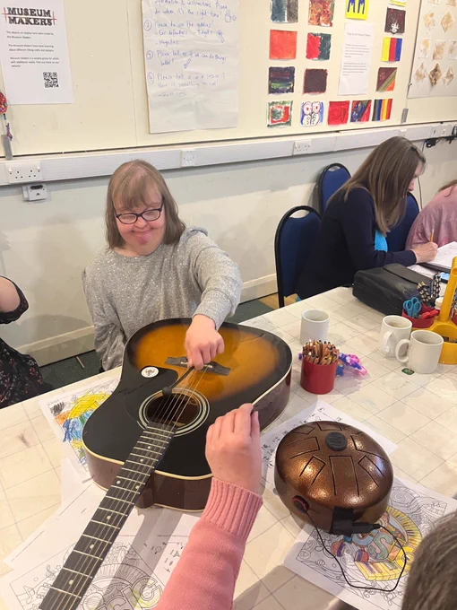 lady with mousey brown hair playing a guitar 