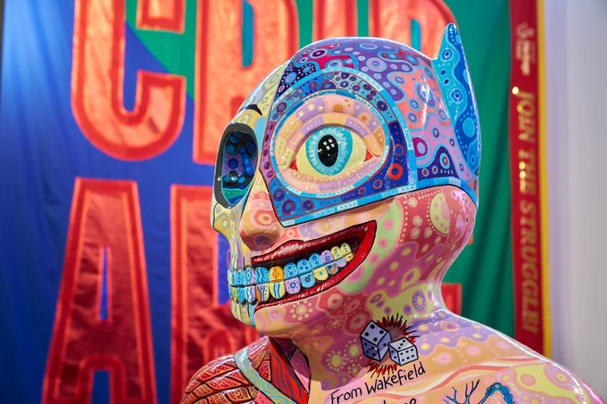A stylised head with colourful shapes grinning, with a giant primary coloured banner behind them.