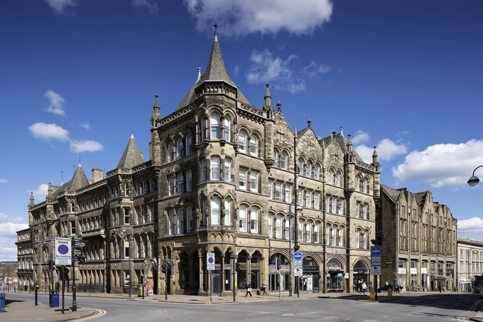 A photograph of a 4-storey historic building on a street corner with a blue sky in the background
