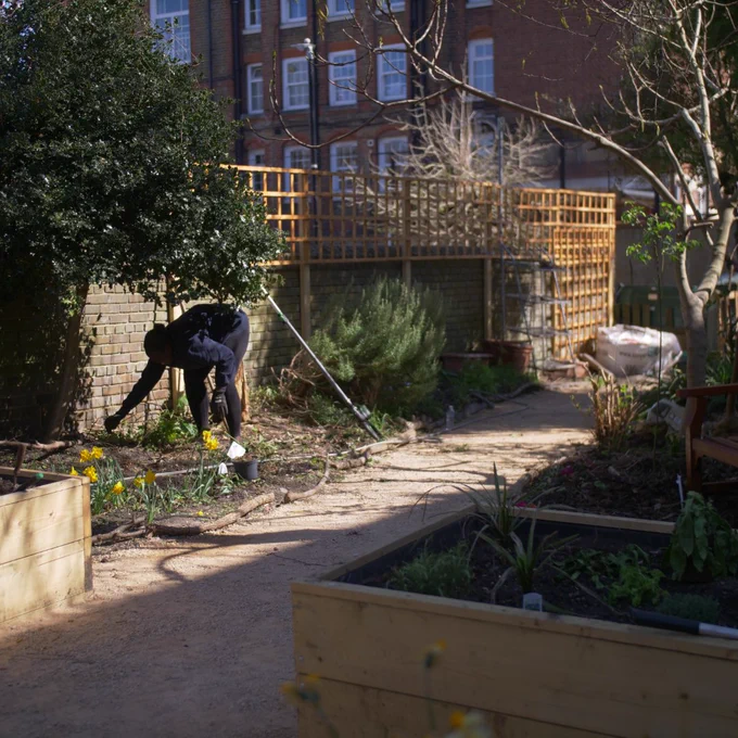 Woman working in the same garden which is now much tidier and has raised beds.