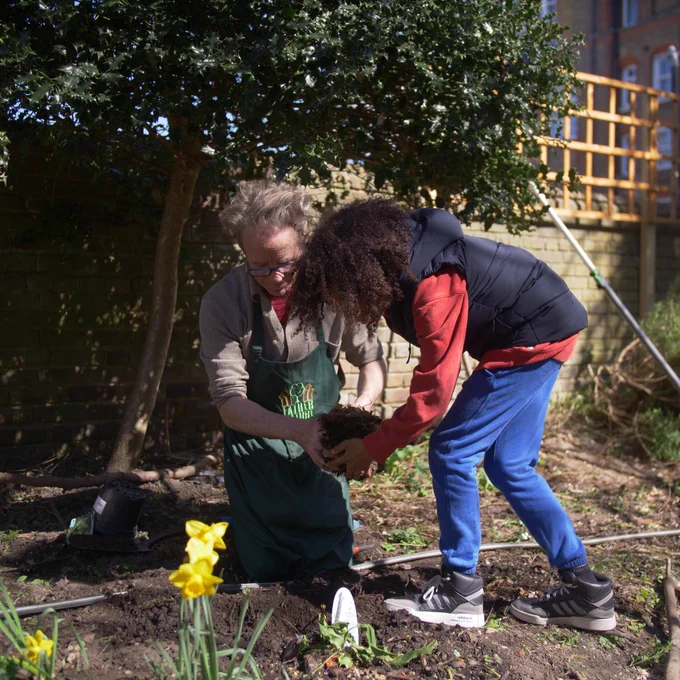 boy aged 11 helps man fill a hole with soil