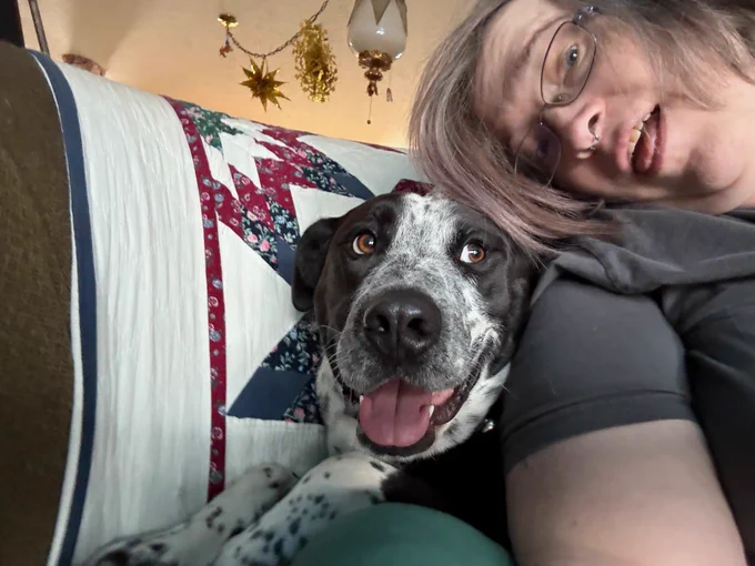 Black-and-white dog sitting on a couch with a woman.