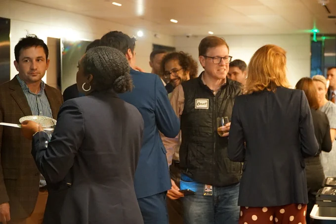 Various pockets of groups mingling over food and drink at reception.