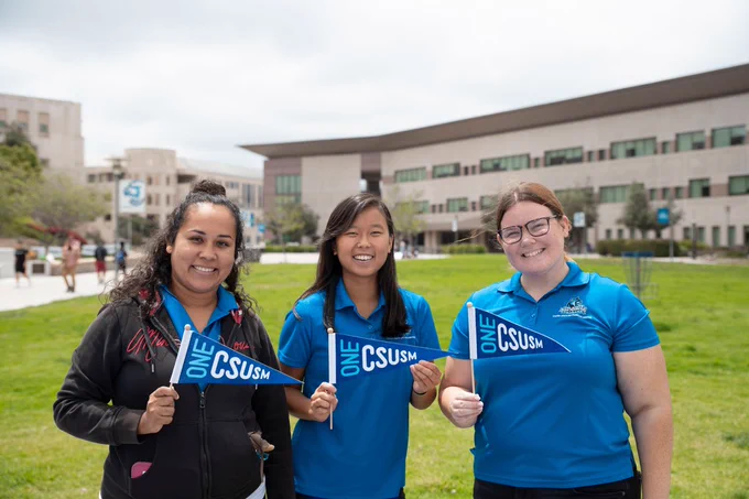 Three students stand in front of the University Library
