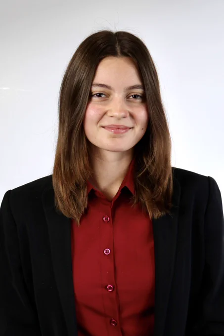 Image of Samantha Schulte wearing a black blazer and red button down, smiling at the camera.