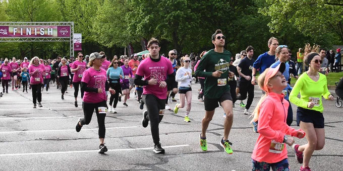 runners of all ages running with green trees in background