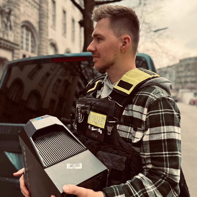 Ein Polizist in Zivil trägt einen Computer