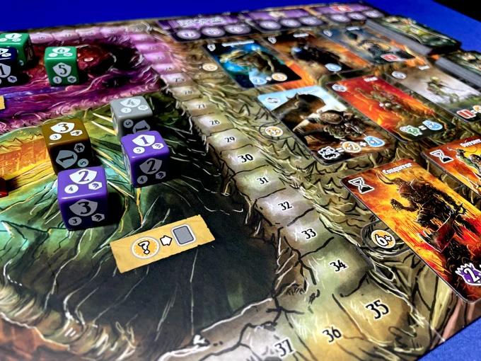 A closeup of the board from Shadow Kingdoms of Valeria. There are a couple purple dice next to the champion cards.