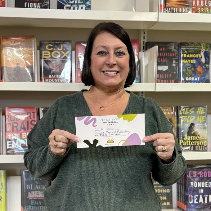 One lucky winter reading winner holds up her gift certificate to About Time Bookstore.