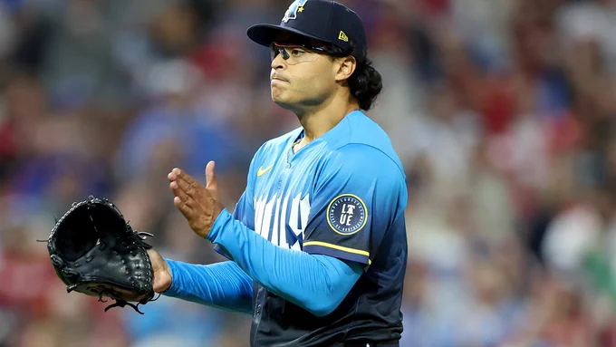 Jesús Luzardo smacks his glove after recording a strikeout. He is wearing a blue Phillies City Connect uniform with white and yellow outline.