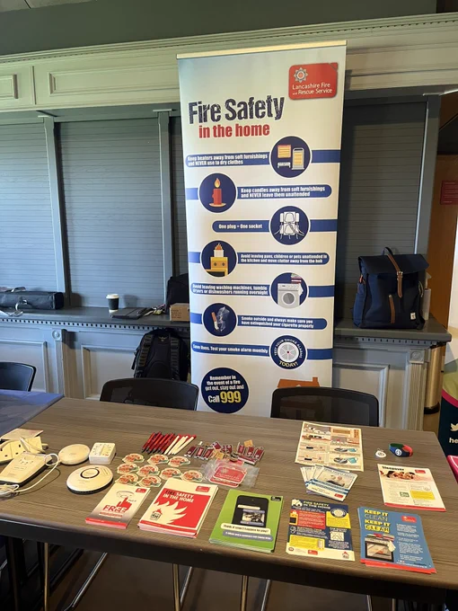 Picture of table with fire safety leaflets, fire safety equipment and a fire safety banner, which is setup in Lancashire FA in Leyland.