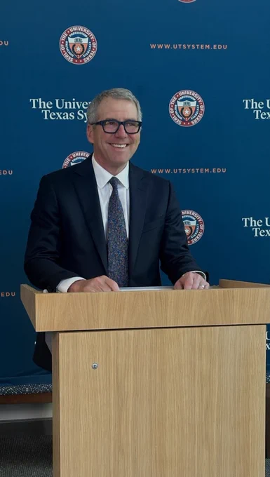 Chancellor Milliken stands at a podium in front of a UT system backdrop. 