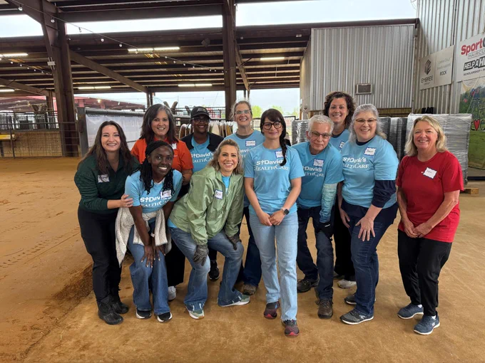 St. David's HealthCare team members gathered as a group in the barn, smiling.