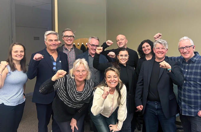 OPSEU/SEFPO leaders celebrate workers' victory in a group photo with fists raised.