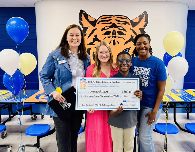 Boy and three ladies holding a big check
