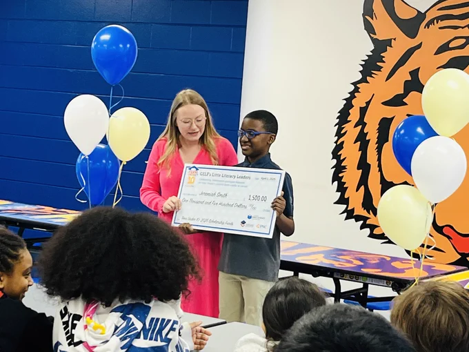 Boy and lady holding a big check