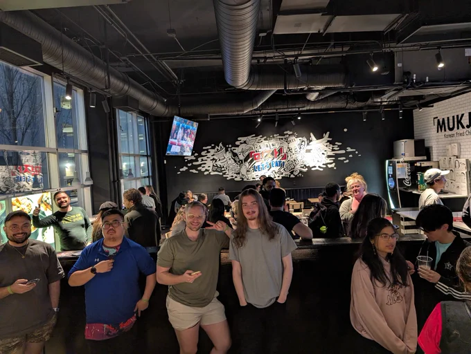 Large groups of people socializing with a few people posing for the camera. A man gives a thumbs up at the camera