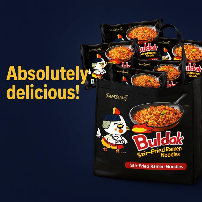 A promotional banner featuring a black reusable shopping bag placed in the center of the image, filled to the top with several packs of Samyang Buldak Hot Chicken Flavor Ramen. The packaging is vivid and eye-catching, with dominant red and black colors, bold white and yellow Korean and English text, and a cartoon chicken character named Hochi, breathing fire and wearing a red bandana. The background is a dark navy blue with soft lighting and a subtle texture, creating contrast and making the ramen packs visually pop. There is no overlaying text on the image, allowing the focus to remain fully on the product. The image conveys abundance, spice, and the popularity of the product, suggesting it’s ideal for stocking up.