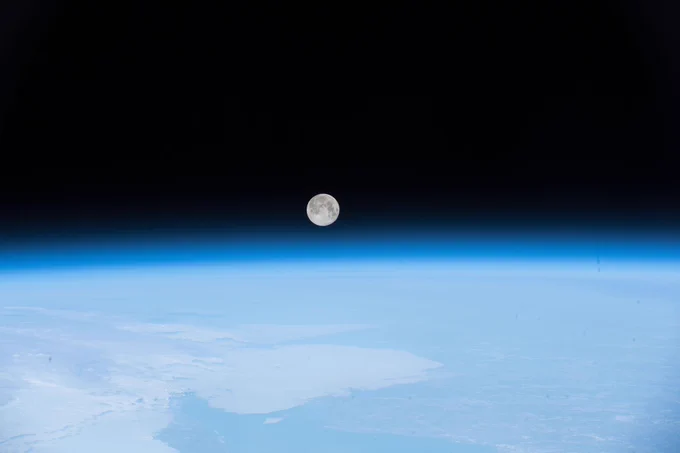 The full moon was pictured April 30, 2018, as the International Space Station orbited off the coast of Newfoundland, Canada. The Moon sits in the center of the image, above the blue glow of Earth's atmosphere. Credit: NASA
