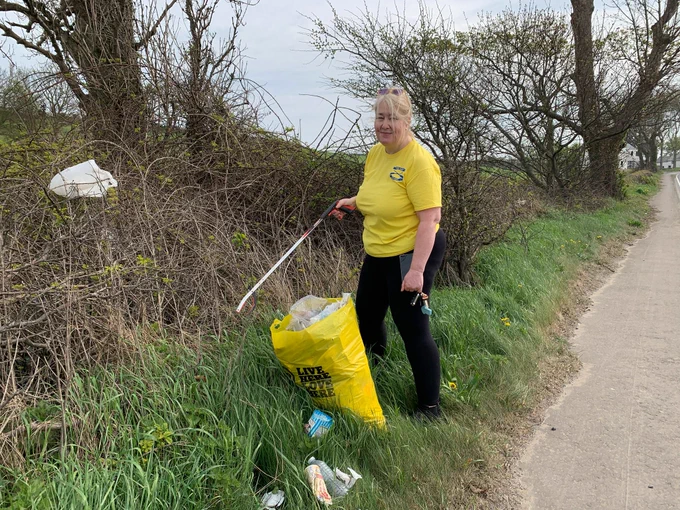 Photo of me picking litter from the hedgerow 