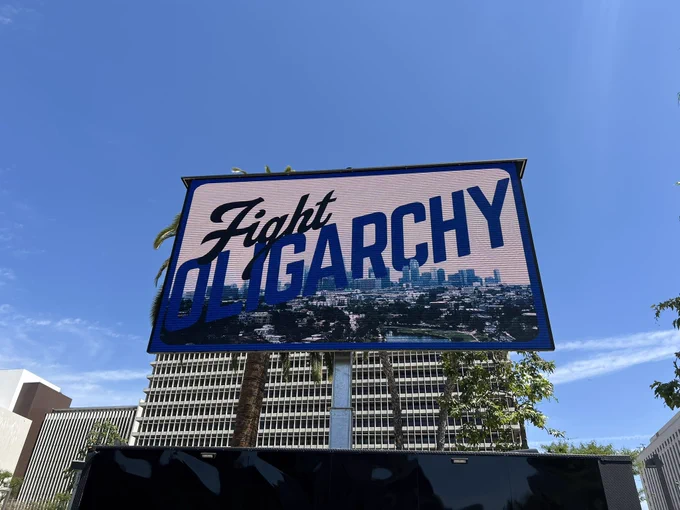 A large billboard with the words “Fight Oligarchy” over a photo of the LA skyline.