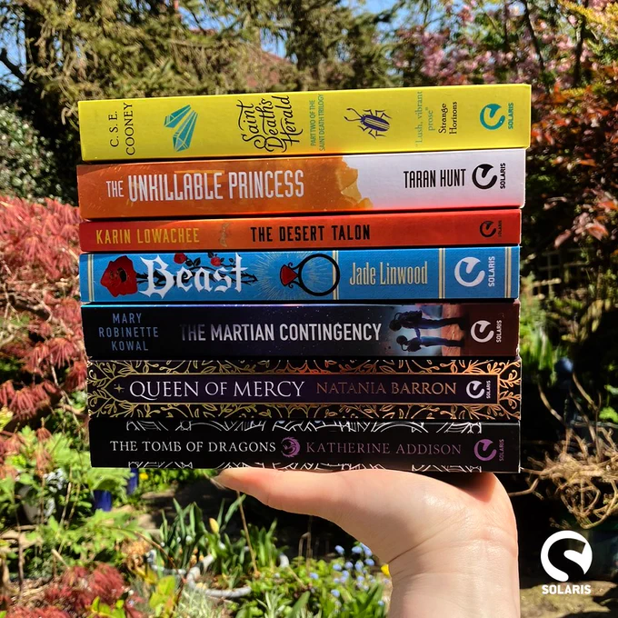 A stack of paperbacks balances on an upturned palm against a garden background with the white Solaris logo in the corner.

Books include:
SAINT DEATH'S HERALD by C. S. E. Cooney
THE UNKILLABLE PRINCESS by Taran Hunt
THE DESERT TALON by Karin Lowachee
BEAST by Jade G. Linwood
THE MARTIAN CONTINGENCY by Mary Robinette Kowal
QUEEN OF MERCY by Natania Barron
THE TOMB OF DRAGONS by Katherine Addison