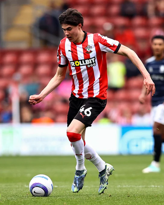 Jay Robinson runs with the ball at his feet during the game against Aston Villa, wearing Saints' red and white striped home kit.