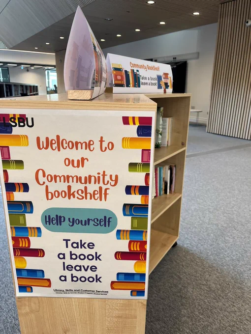 Close up of the poster on the side of the Community Bookshelf. Text: Welcome to our Community bookshelf, Help yourself, Take a book leave a book