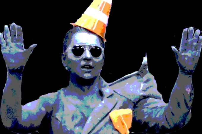 Photo of artist Nicola Smith in Haphazard 2019 — a woman wearing sunglasses and an orange traffic cone on her head, set against a black background.