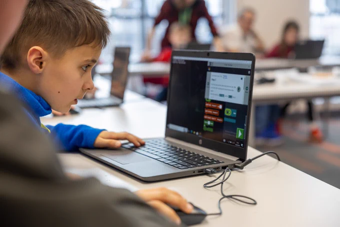 Photo showing a young boy coding on a laptop using Minecraft Education