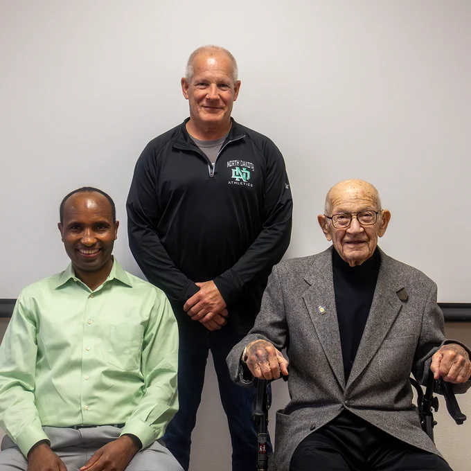 Three men sit for a group photo