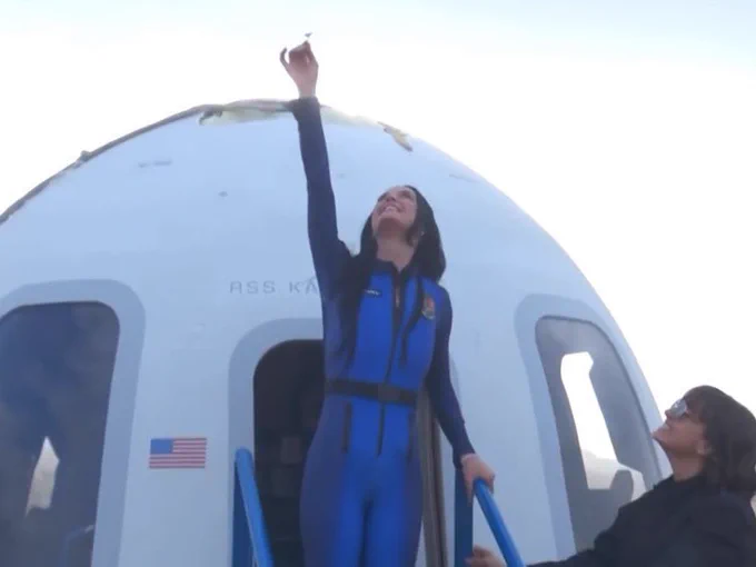 Katy Perry landing back on Earth after going to space.