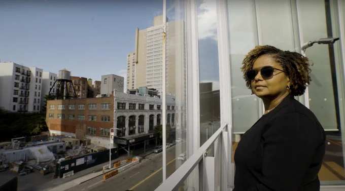 Professor Sheila Foster stands on a balcony overlooking an urban street scene.