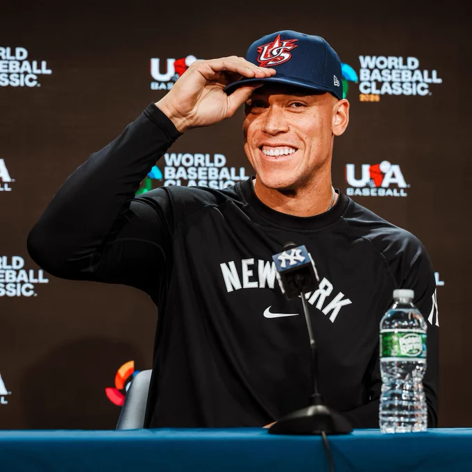 Aaron Judge puts on his Team USA cap during a press conference. 
