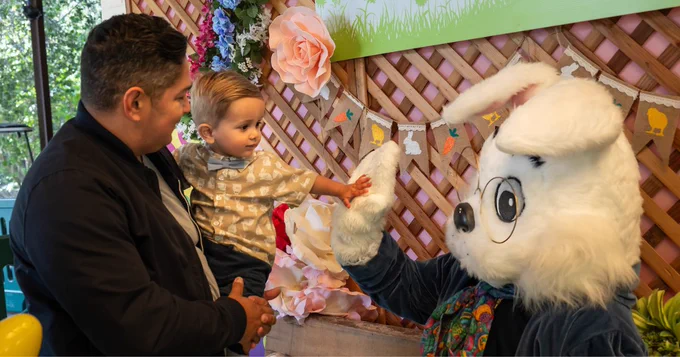 An adult and toddler interacting with the Big Bunny costumed character at the L.A. Zoo.